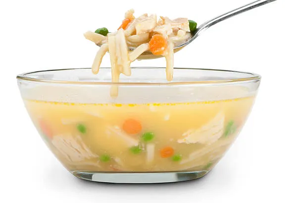 A bowl of chicken soup with a spoon